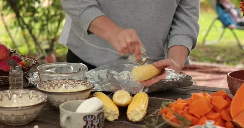 Hands add salt from salt shaker and spice over raw corn cob before grilling Stock Footage 164589718