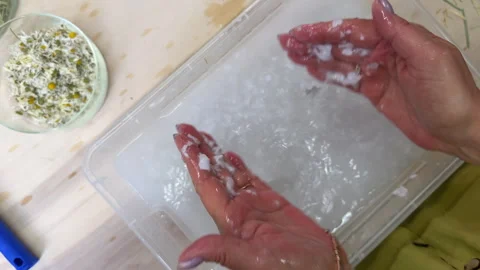 Hands adding dried chamomile flowers and grass to paper pulp mixture. Natural de Stock Footage 313501944