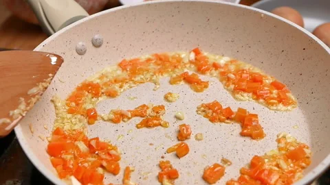 Hands adding eggs into the frying pan with fried vegetables for healthy cooking. Stock Footage 158658301