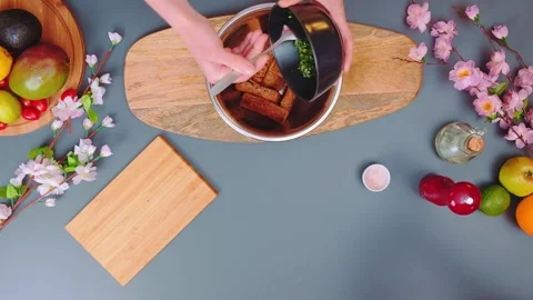 Hands adding green sauce to croutons on wooden cutting board indoors Stockbeeldmateriaal 342837747