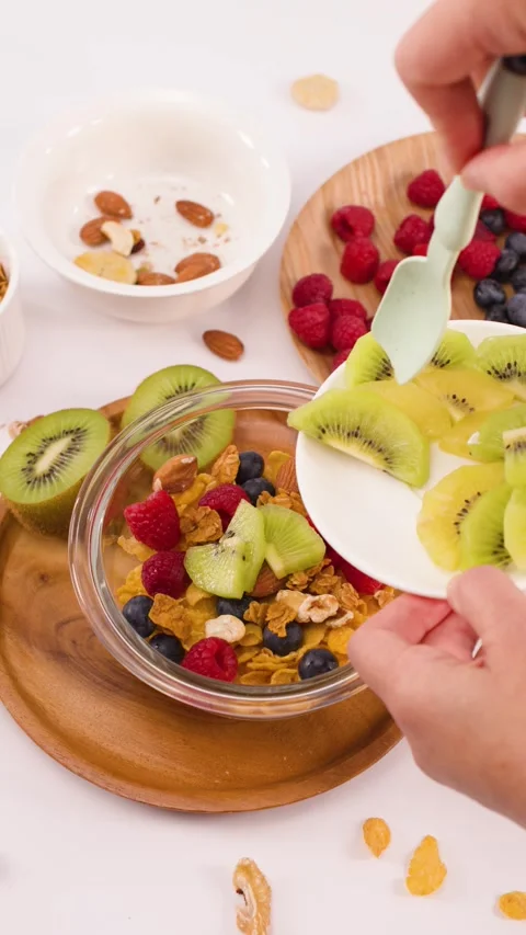Hands Adding Sliced Kiwi to a Healthy Breakfast Cereal Bowl Stock Footage 337519897