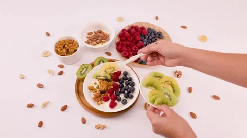Hands Adding Sliced Kiwi To Healthy Greek Yogurt Breakfast Bowl Stock Footage 337770737