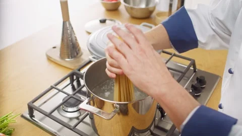 Hands Adding Spaghetti to Cooking Pot Stock Footage 345267649