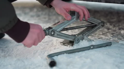Hands Adjust Jack on Snowy Ground for Car Repair Setup Видео 310187843
