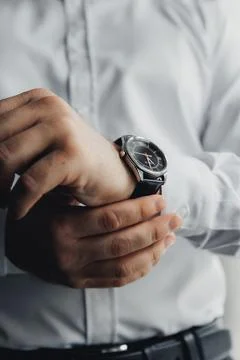 Hands adjust a sleek, dark watch on a wrist Foto stock