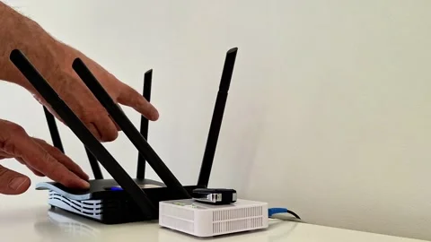 Hands Adjusting Antennas on Black Wireless Router with Connected Modem Stock Footage 333230074