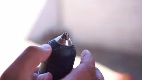 Hands adjusting a drill chuck to loosen the bit holder. Tool footage showing Stock Footage 346248133