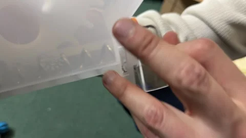 Hands adjusting plastic container with orange latch mechanism during equipment Video stock 336977298