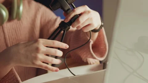 Hands adjusting RGB condenser microphone on desktop tripod beside computer Stock Footage 343542046