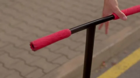 Hands adjusting scooter handlebars with red foam grips outdoors Stockbeeldmateriaal 347202267