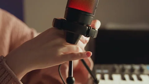 Hands adjusting tabletop microphone in shock mount above small tripod with warm Stock Footage 343543655