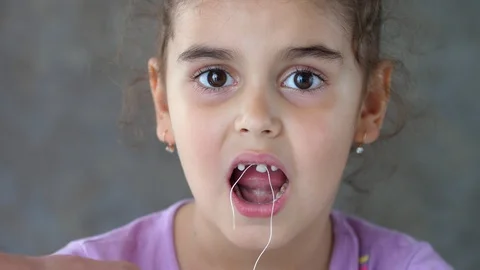 The hands of an adult pull the thread tied to the child's tooth. Failed attempt Stock Footage 119277242