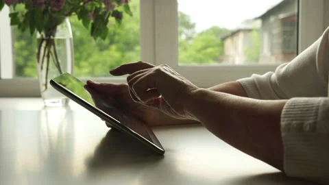 The hands of Aged woman using a digital tablet PC at home Stock Footage 142340495