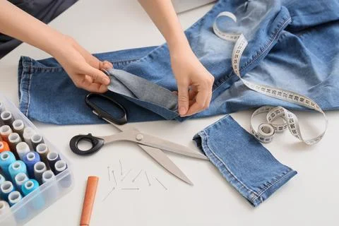 Hands altering denim jeans with sewing tools Stock Photos