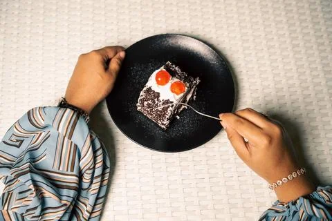 Hands and a fork cut into a slice of black forest cake roll with cream and ch Foto stock