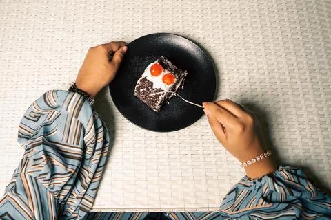 Hands and a fork cut into a slice of black forest cake roll with cream and ch Foto stock