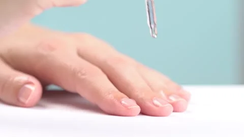 Hands and nails care concept. A woman using a pipette applies moisturizer s.. Stock Footage 277976608