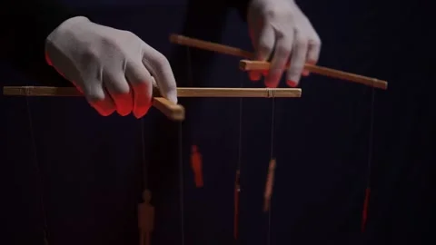 The hands of an anonymous puppeteer manipulate human puppets. The concept of Stock Footage 221455057