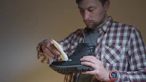 Hands apply polish to a leather boot, demonstrating practical shoe care. The Stock Footage 334212738