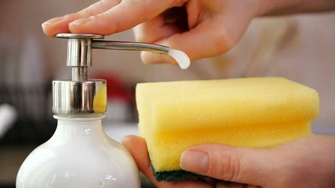 Hands apply washing up liquid from recipient on sponge - close-up 스톡 동영상 104463629