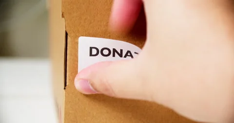 Hands applying DONATIONS Sticker label on a cardboard box with barcode Stock Footage 199064499