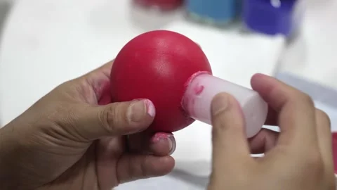 Hands Applying a Glossy Red Finish to a Clay Sphere Stock Footage 340901144