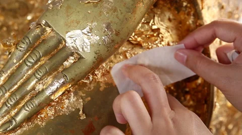 Hands applying gold leaf on revered buddha statue,HD video Stock Footage 53855172