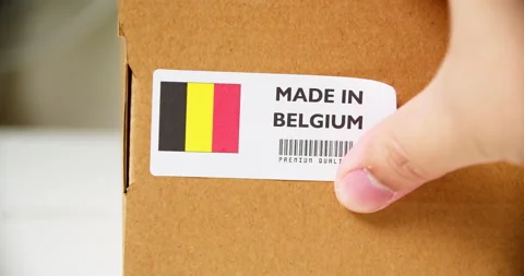 Hands applying MADE IN BELGIUM flag label on a shipping cardboard box with Stock Footage 199611765
