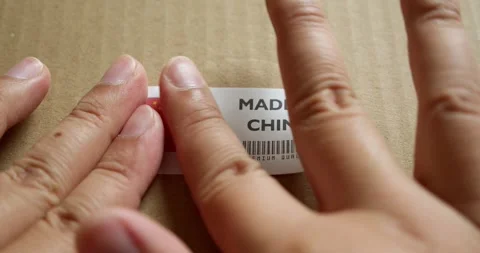 Hands applying MADE IN CHINA flag label on a shipping box with product Stock Footage 254105073