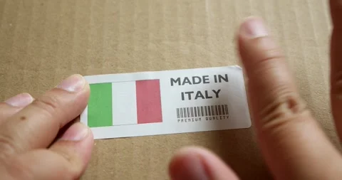 Hands applying MADE IN ITALY flag label on a shipping box with product Stock Footage 254105086