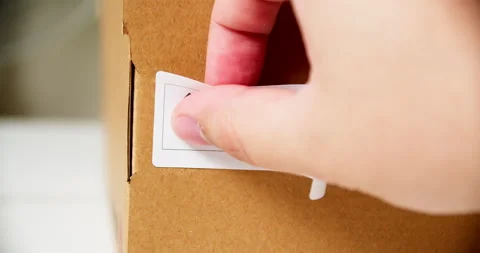 Hands applying MADE IN KOREA  flag label on a shipping cardboard box with Stock Footage 199009174