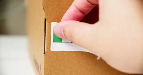 Hands applying MADE IN MEXICO flag label on a shipping cardboard box with Stock Footage 199026540