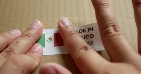 Hands applying MADE IN MEXICO flag label on a shipping box with product Stock Footage 254105001