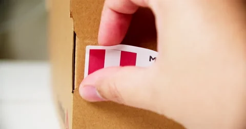 Hands applying MADE IN PERU flag label on a shipping cardboard box with Stock Footage 199026654