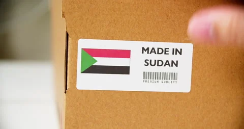 Hands applying MADE IN SUDAN flag label on a shipping cardboard box with Stock Footage 199288709