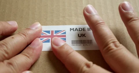 Hands applying MADE IN UK flag label on a shipping box with product Stock Footage 253384257