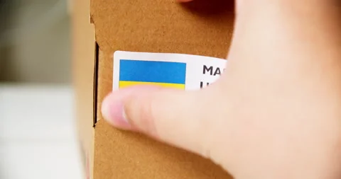 Hands applying MADE IN UKRAINE flag label on a shipping cardboard box with Stock Footage 199004941