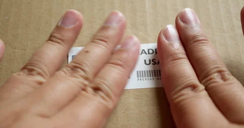 Hands applying MADE IN USA flag label on a shipping box with product Stock Footage 253450697