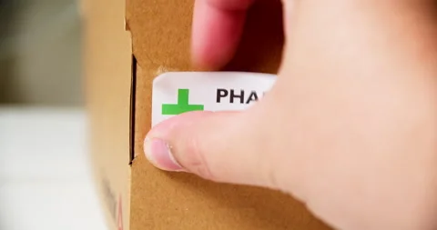 Hands applying +PHARMACY Sticker label on a shipping cardboard box. Stock Footage 199064438