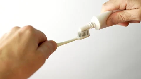 Hands applying toothpaste to a toothbrush, close-up Stock Footage 252896478