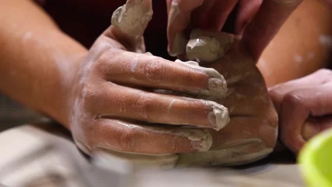 The hands of an apprentice and the hands of a master forming a ceramic pot Video stock 245782681