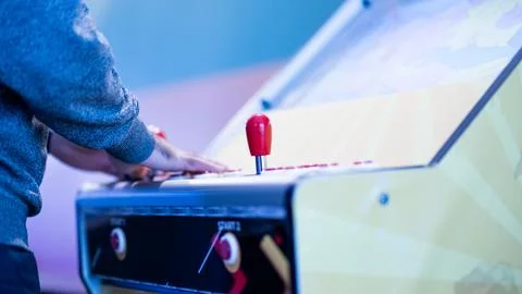 Hands on an arcade machine control panel with a red joystick Stock Photos