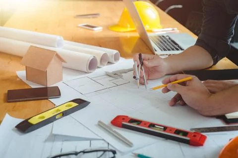 Hands of architect or engineer using compass working with blueprint on desk i Stock Photos