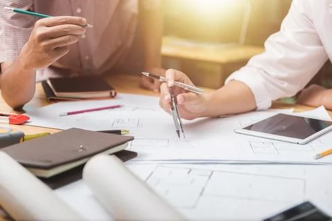 Hands of architect or engineer using drawing compass with blueprint on desk i Stock Photos