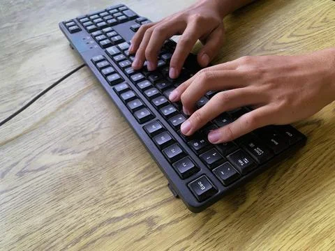 Hands are actively typing on a computer or laptop keyboard, daily work activity Stock Photos