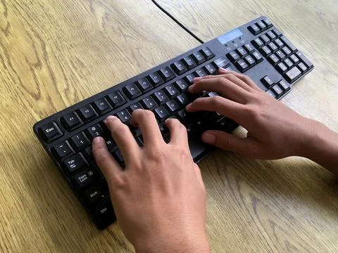 Hands are actively typing on a computer or laptop keyboard, daily work activity Stock Photos