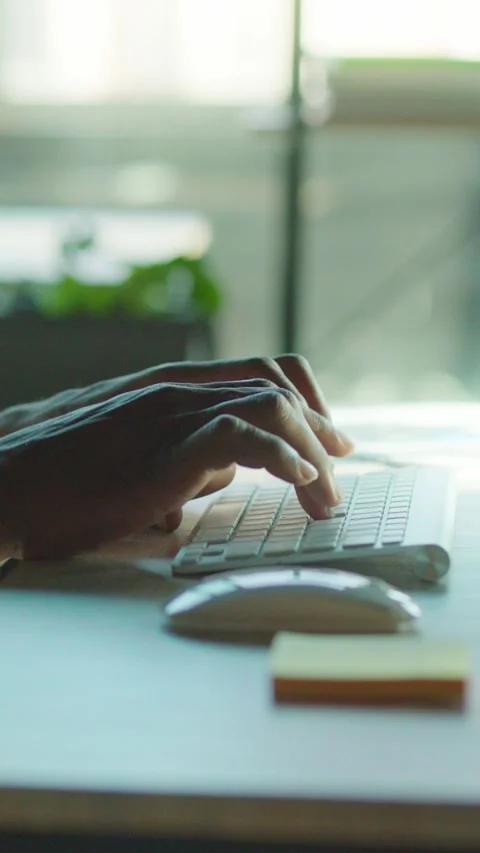Hands are actively typing on a keyboard within a modern and efficient workspace Stock Footage 314208785