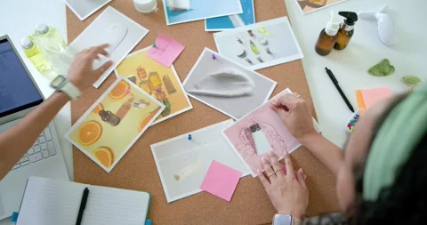 Hands are arranging prints and pink notes on corkboard at desk after review to Stock Footage 344851201