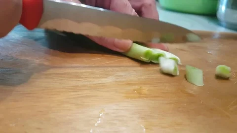 Hands are cutting a green onion on a wooden board Stock Footage 80880028