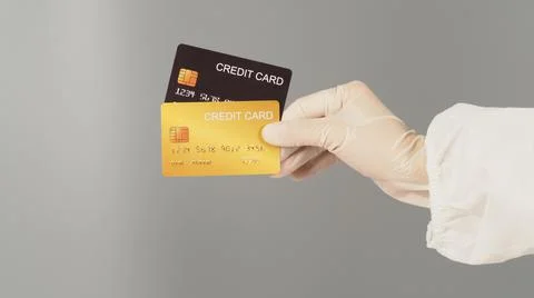 Hands are holding two black and gold credit cards on grey background. Hand we Stock Photos